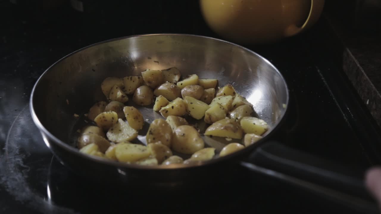 Cooking A Delicious Sliced Of Potatoes In A Pan With Basil Leaf - Close Up Shot