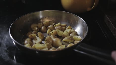 cooking a delicious sliced of potatoes in a pan with basil leaf - close up shot