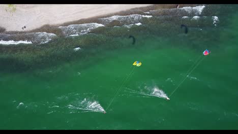 Drone-following-two-Kite-Boarders-on-the-beach-in-the-Sea-of-Galilee,-Israel