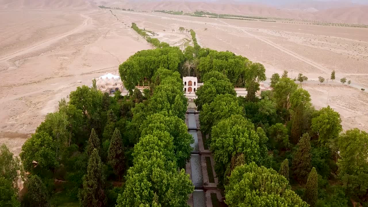 un jardín persa verde con árboles y corriente de agua en medio del desierto en kerman irán
