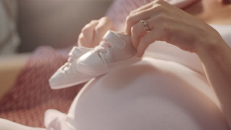 pregnant woman holding baby shoes