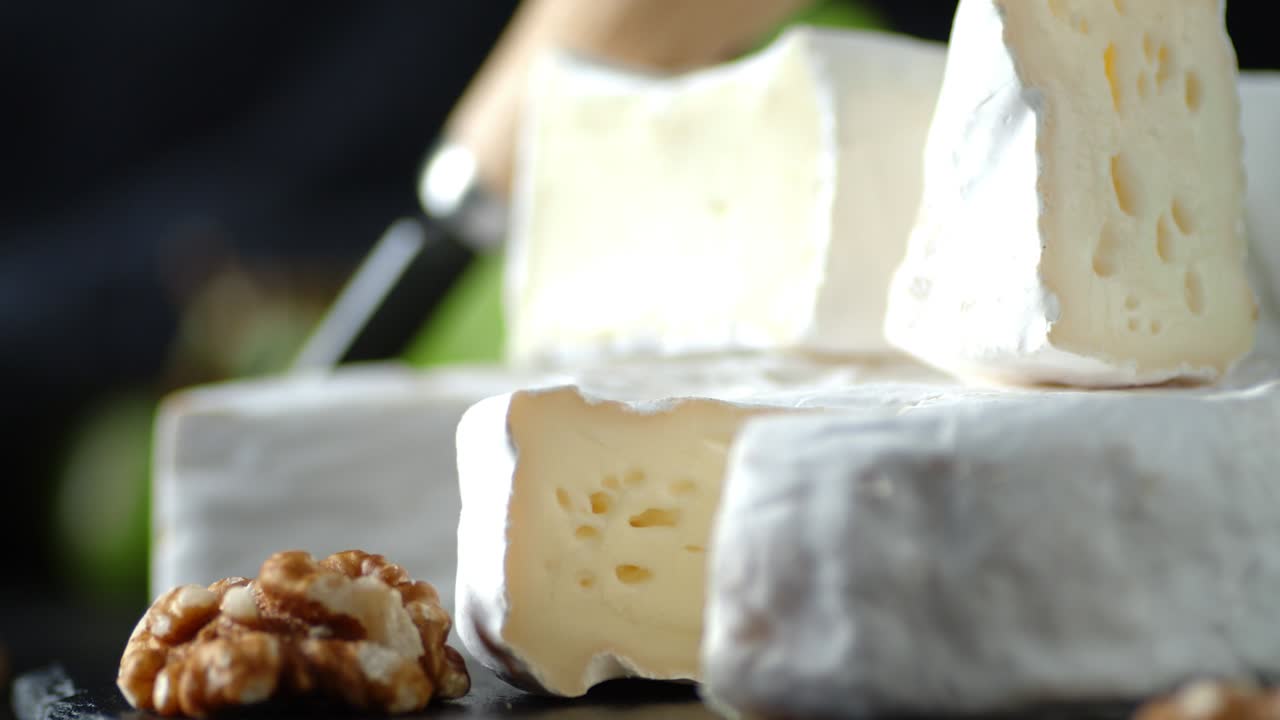 Pieces Camembert cheese with walnuts and grapes slowly rotate.
