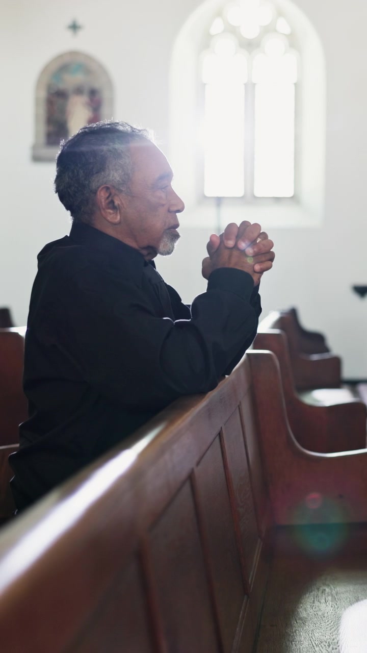 Senior Man Praying in a Church Pew