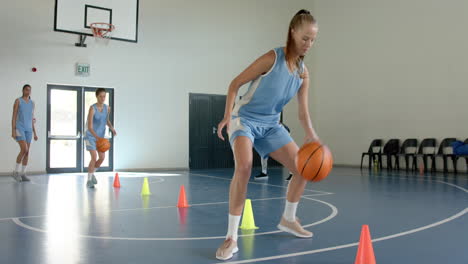playing basketball, woman dribbling ball around cones in gymnasium training session