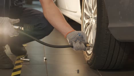 filling the wheel with air from the compressor at the service station. service station, close-up man checking tire pressure, car repair and tyre inflation. professional tire fitting at car service