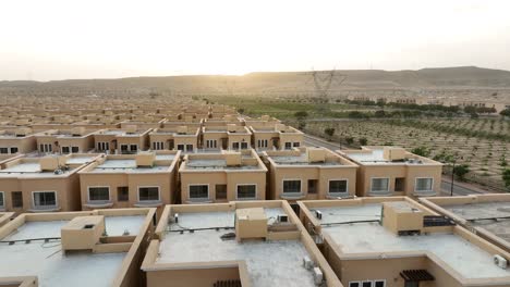 aerial view of rows of modern houses bahria town housing estate in karachi with sun setting on horizon