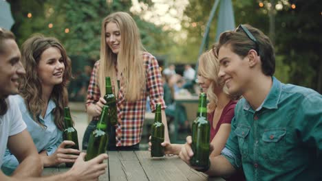 friends drinking beer and toasting at outdoor party