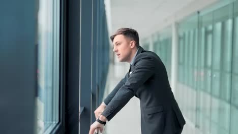 Closeup,-handsome-man-in-business-suit-standing-at-window-aggressively-knocking-and-angry