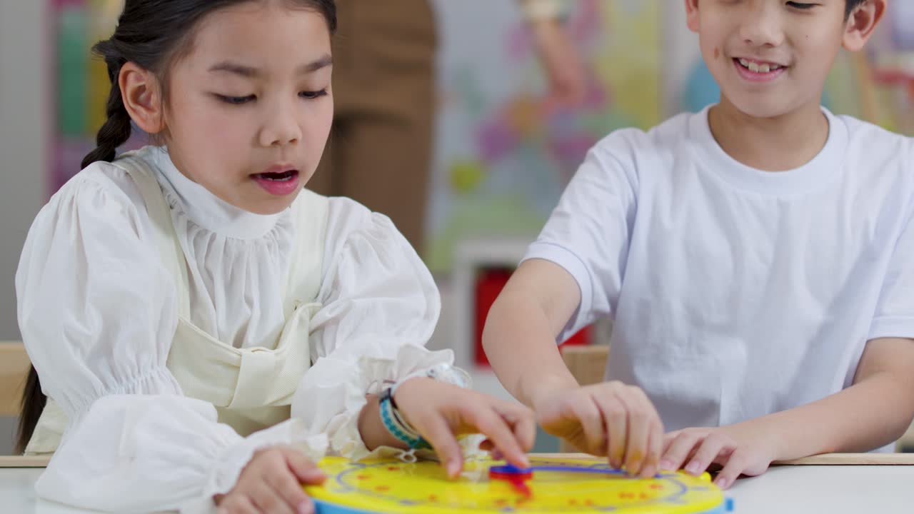 明るい教室で、2人の子供が黄色い時計のおもちゃを使って時間の概念を学ぶ