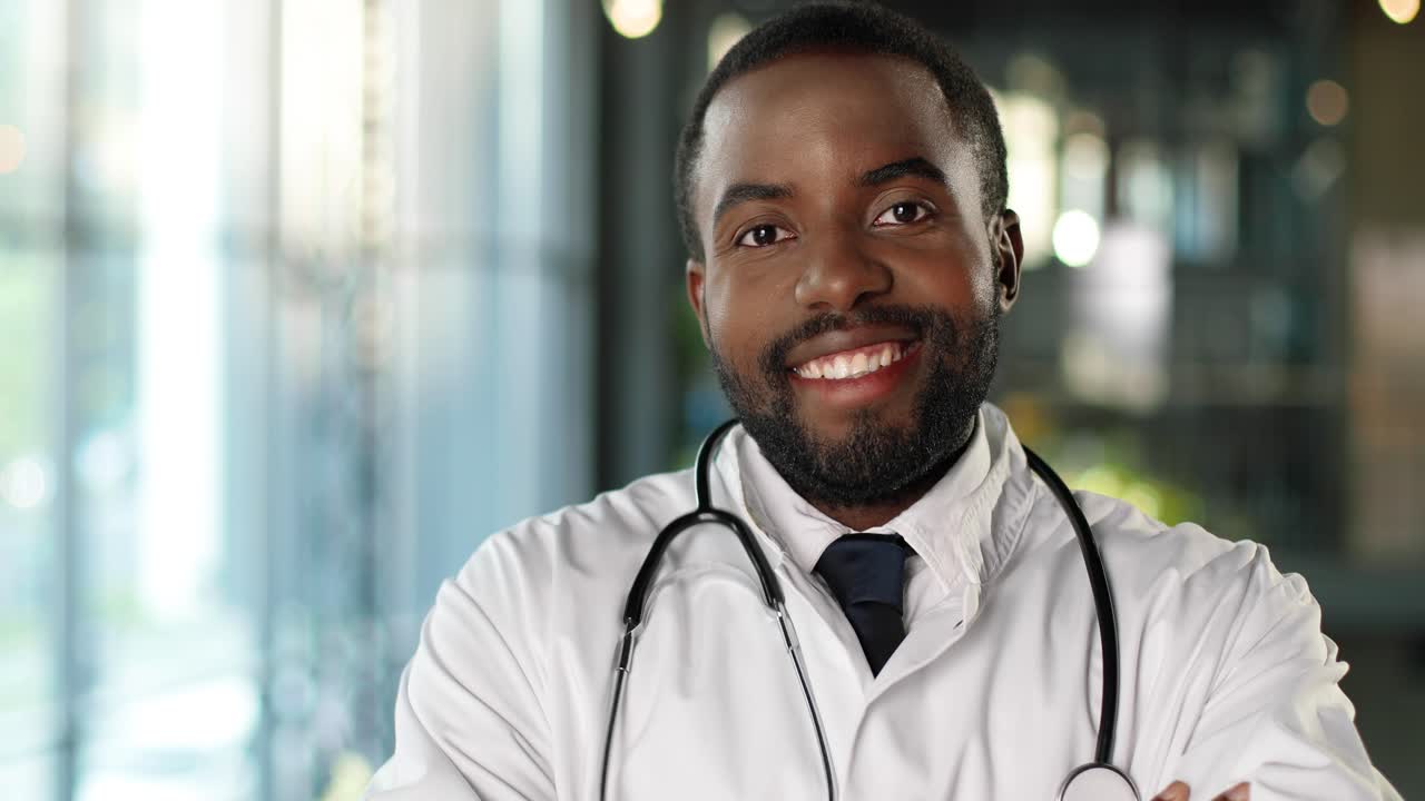 Portrait d'un médecin afro-américain souriant joyeusement, avec un stéthoscope, regardant la caméra.