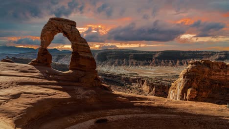 scenic and cinematic dark thunderstorm clouds time-lapse at the famous delicate arch rock among the arches national park hiking landmarks in utah, arizona, america usa. cinemagraph seamless video.