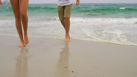 low section of couple walking with hand in hand on the beach 4k