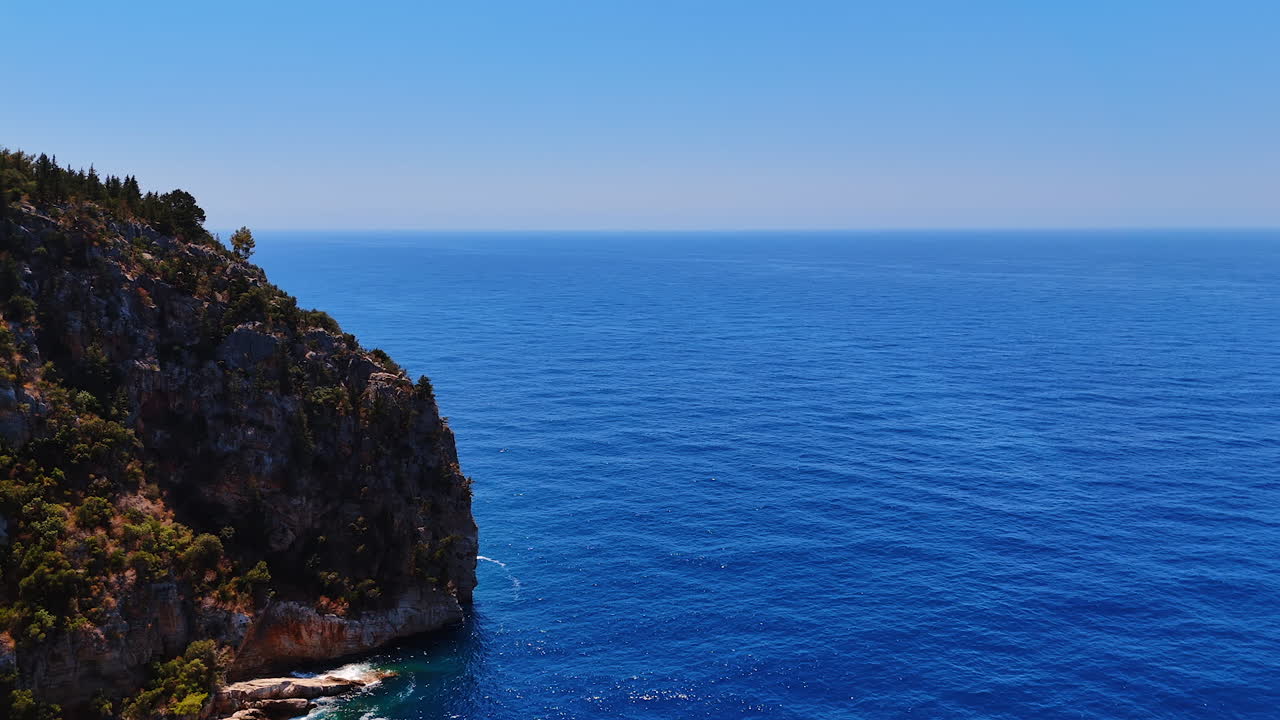 Blue ocean view under clear sky. The expansive blue ocean stretches to the horizon, flanked by rugged cliffs under a bright, clear sky
