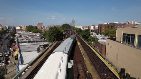 an aerial view of elevated train tracks with three vintage train cars travelling away from the camera on a sunny day