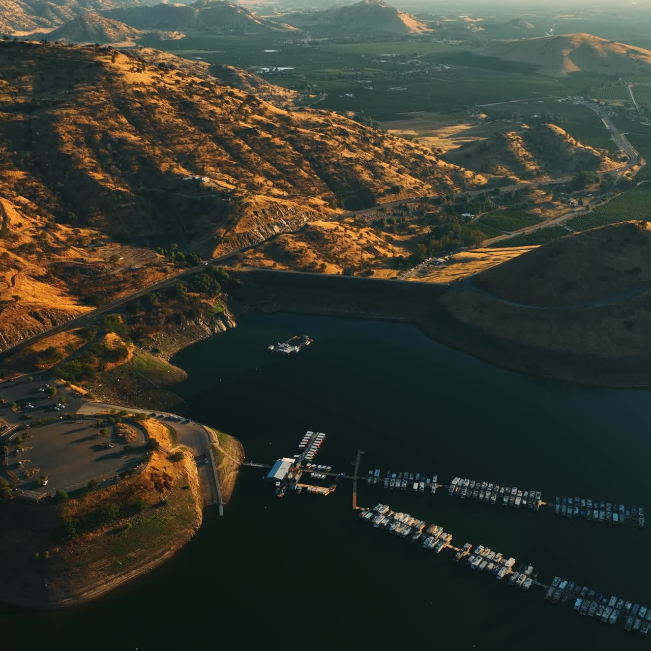 Beautiful lake with dock for yachts and boats surrounded by mountains in California. Lovely green valleys behind the rocks at backdrop