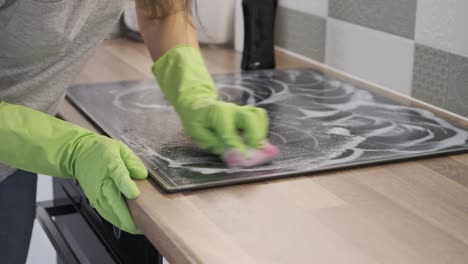 closeup of hand woman cleaning modern cooking glass ceramic electric surface with sponge and detergent