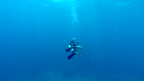 lone scuba diver swimming through the open blue ocean unreeling a guide rope