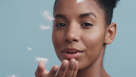 close up beauty portrait beautiful african american woman playfully blowing feathers falling touching bare skin enjoying soft skincare gently caressing gorgeous body feminine perfection in slow motion