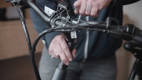 el hombre usa una llave allan para establecer la altura de los manillares de una bicicleta eléctrica después de ajustar la altura del eje de dirección