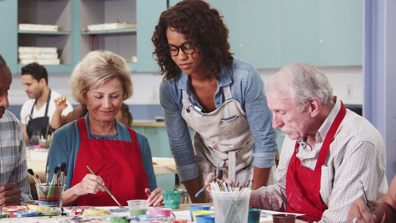은퇴한 노인 그룹이 교사와 함께 커뮤니티 센터에서 미술 수업을 듣고 있습니다.
