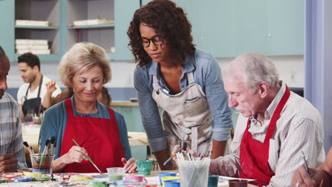 group of retired seniors attending art class in community centre with teacher