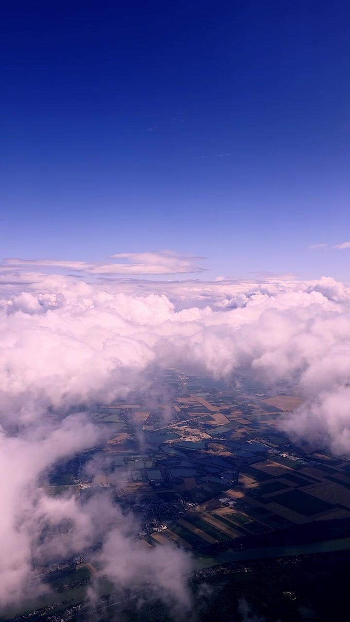 Nuvole bianche fluttuano sopra un paesaggio agricolo a mosaico visto dall'alto in una giornata limpida e soleggiata