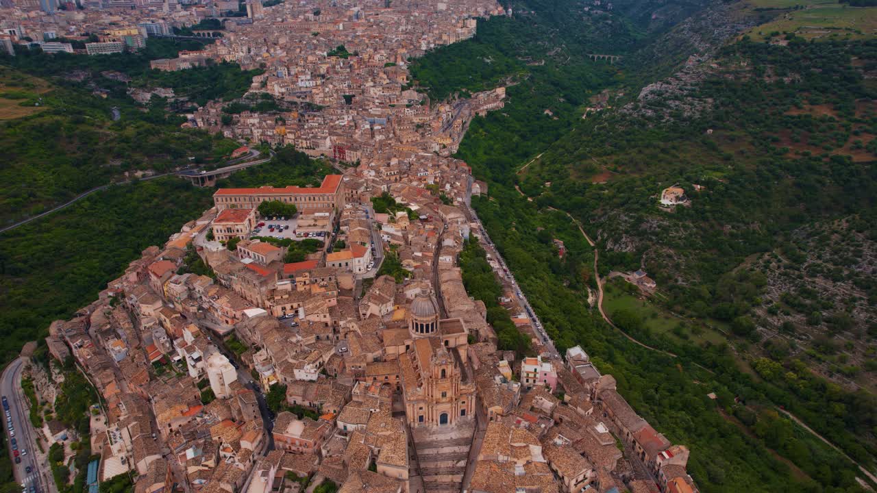 Ragusa Ibla old town with layered tiled rooftops, Baroque cathedral. Scenic aerial, bright daylight