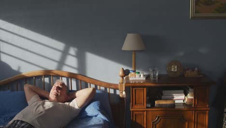 senior man lying on bed at home