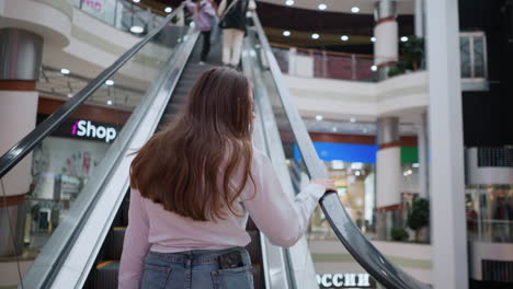 young lady steps onto moving escalator, with other people in front, in modern mall, showcasing everyday urban life and consumer activity