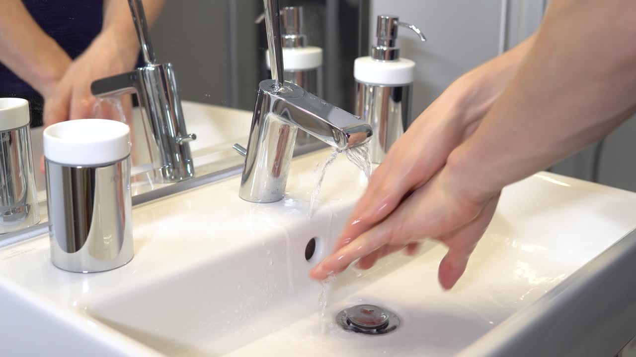 persona desinfectándose las manos con agua de grifo