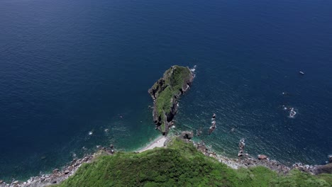 aerial view straight down a steep cliff towards small island in deep blue water along highway 9 in east taiwan