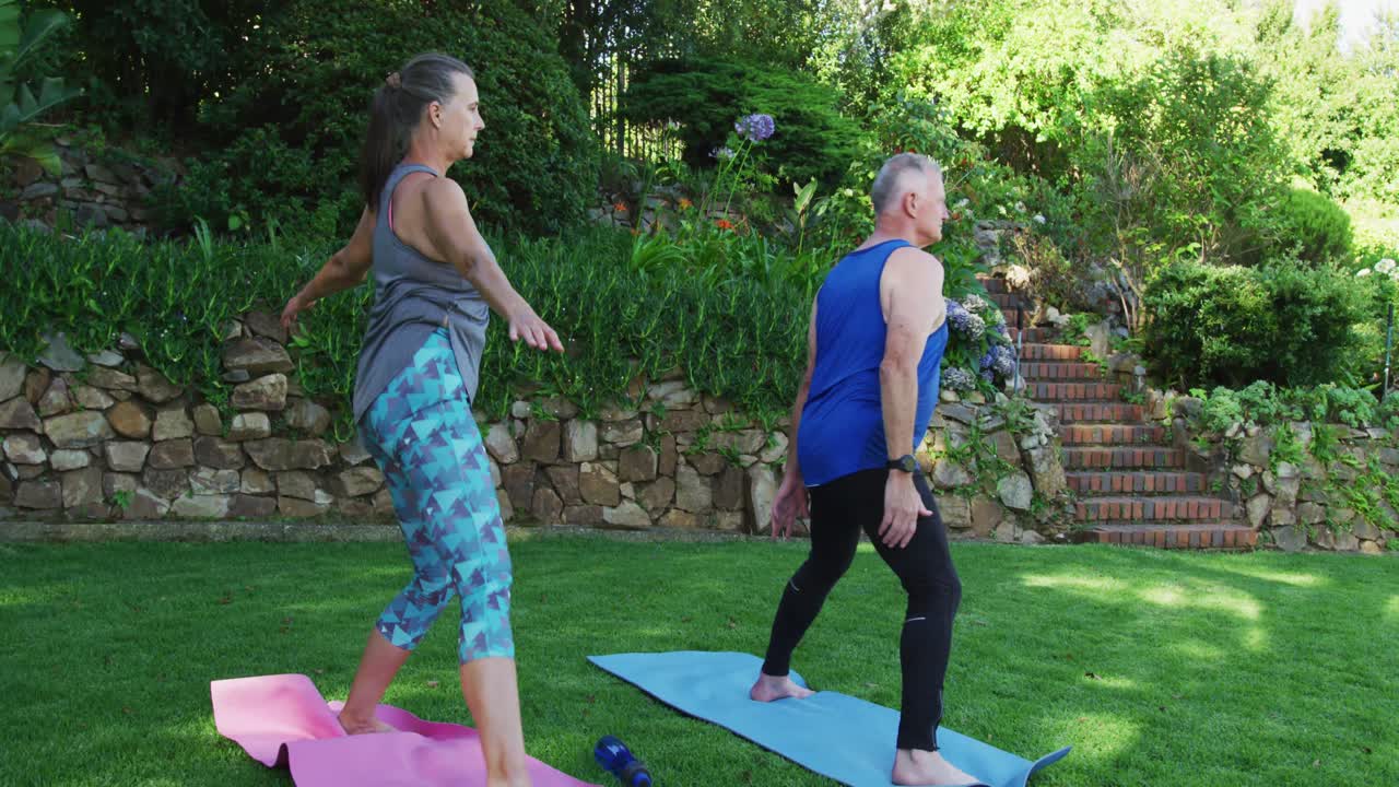 pareja de ancianos caucásicos realizando ejercicios de estiramiento juntos en el jardín