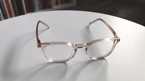 modern eyeglasses in light colour lie on a white table, bright glasses frame, slow motion footage