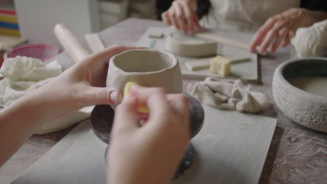 Woman Using Sponge for Making Ceramic Mug on Pottery Wheel