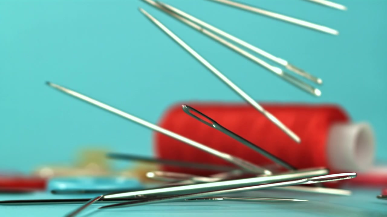 Sewing Needles Falling in Slow Motion with Thread and Buttons