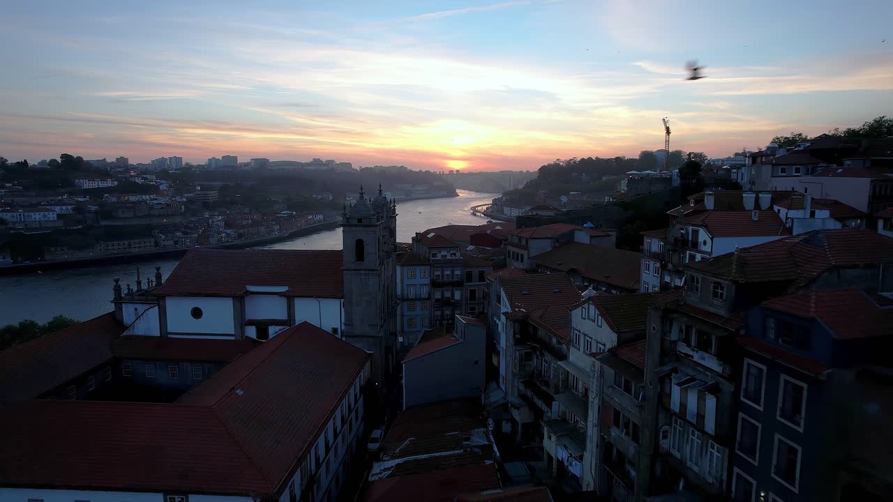 Porto cityscape at sunset, capturing historic architecture and winding Douro River, showcasing Portugal's urban landscape and old European charm from Jardim do Morro, drone glides through buildings