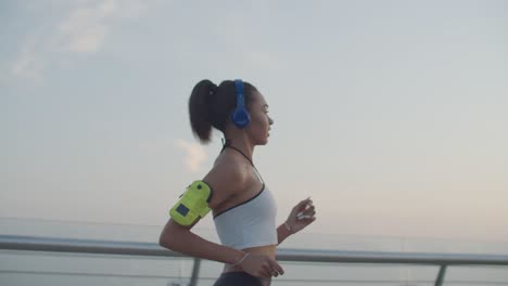 female runner in headphones jogging at sunrise