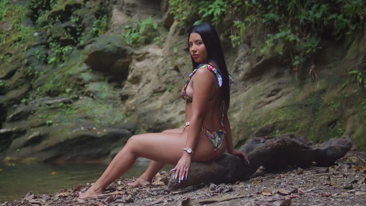 . A girl wearing a bikini by a cascading waterfall in the Caribbean.
