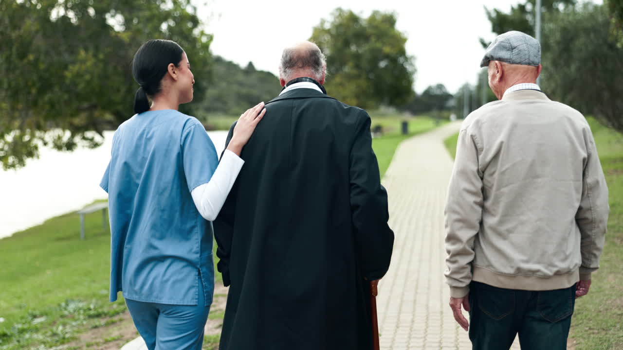 Nurse walking with elderly men in the park