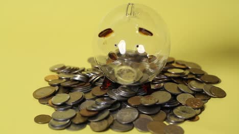 hand putting coins in glass piggy bank standing on a pile of coins.4k