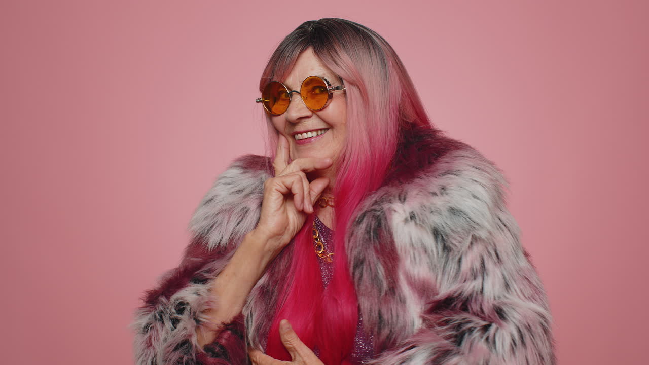 Donna giocosa e felice che indossa occhiali da sole, ammicca alla fotocamera con un sorriso, flirtando.