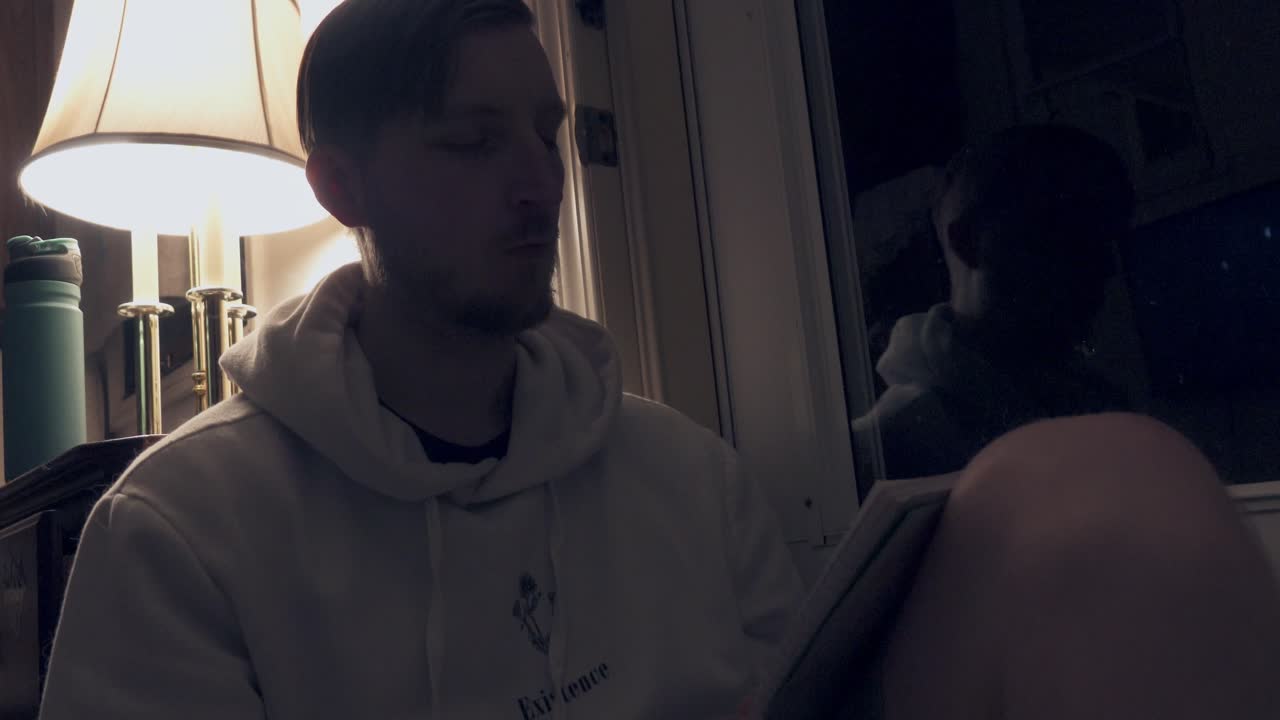 한 남자가 밤에 램프  ⁇ 에 과부  ⁇ 에 노트북을 쓰고 있다.