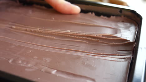 an artist and sculptor carving off brown modeling clay from a large block to begin sculpting his art project in a studio