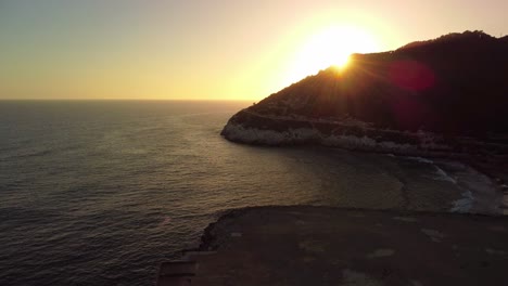 Puesta-De-Sol-Sobre-Costa-Garraf,-Barcelona,-Con-Una-Fábrica-De-Cemento-Y-Un-Mar-En-Calma-Creando-Una-Serena-Vista-Costera.