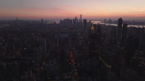 Luftaufnahme-Der-Stadtentwicklung-In-Der-Abenddämmerung.-Kippen-Sie-Nach-Oben-Und-Offenbaren-Sie-Das-Stadtbild-Vor-Dem-Farbenfrohen-Dämmerungshimmel.-Manhattan,-New-York-City,-Vereinigte-Staaten