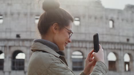 woman taking a picture of the colosseum in rome