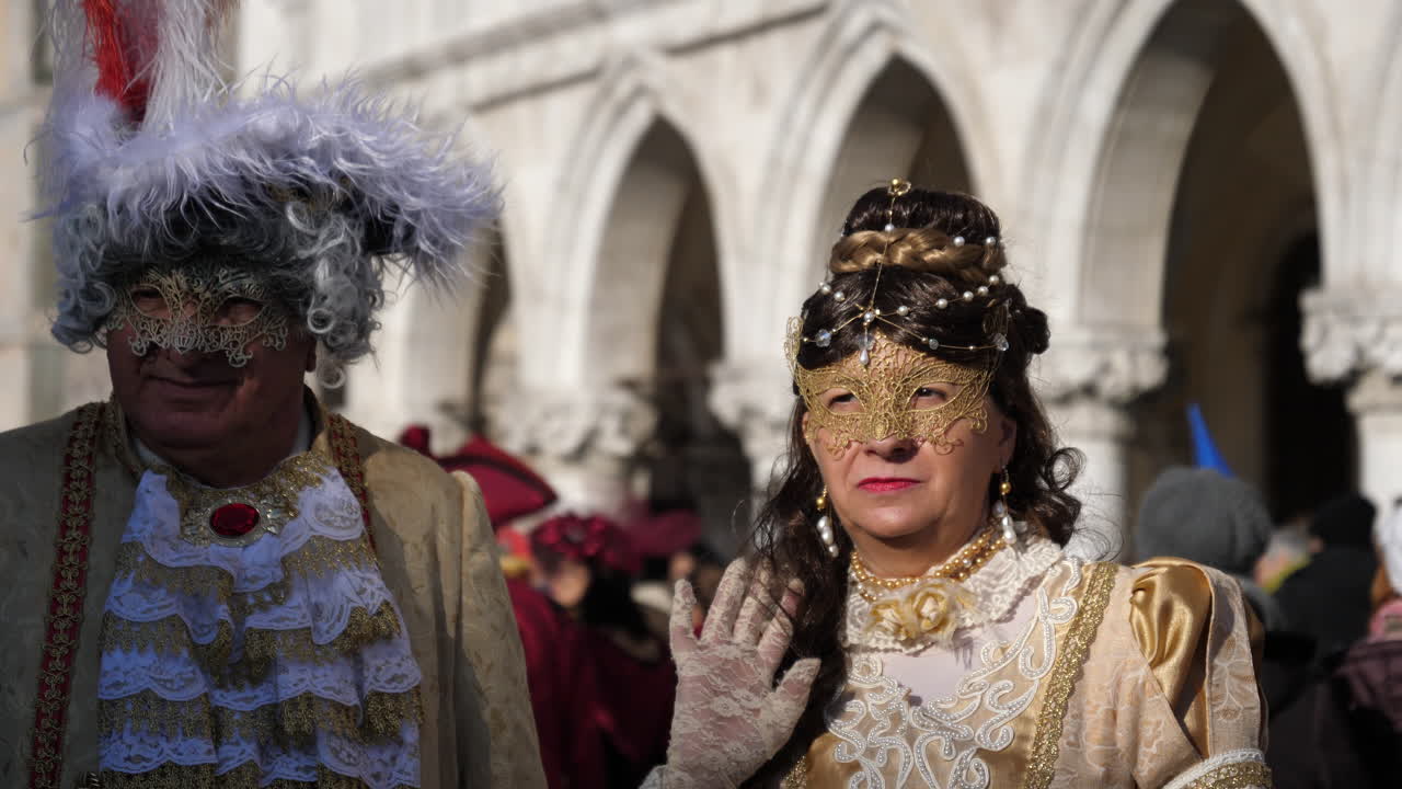 Elder couple use disguise of fancy dress and mask in Venice Carnival and pose