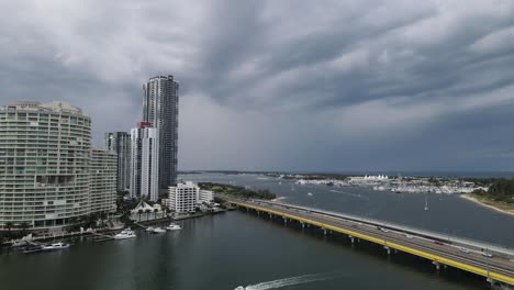 A-high-aerial-view-looking-down-on-a-busy-road-and-tram-bridge-next-to-tall-high-rise-buildings-with-a-stormy-backdrop