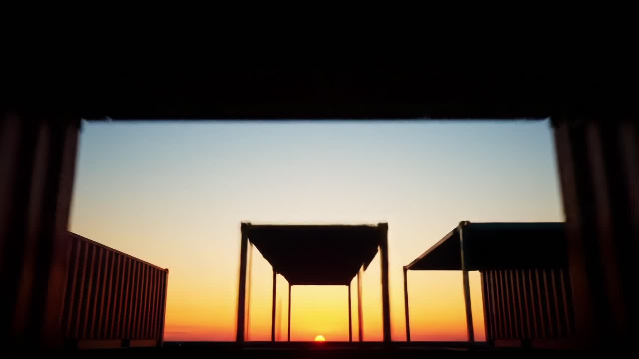 A Stunning Sunset View Framed by Silhouetted Structures, Capturing the Tranquil Beauty of Dusk and the Calmness of the Evening Sky in a Serene Environment