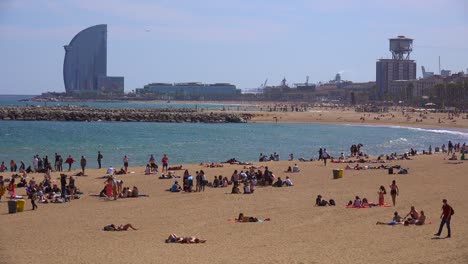 wide shot of sunbathers along the beach in barcelona spain